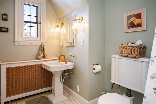 bathroom with radiator heating unit, vaulted ceiling, tile patterned floors, and toilet