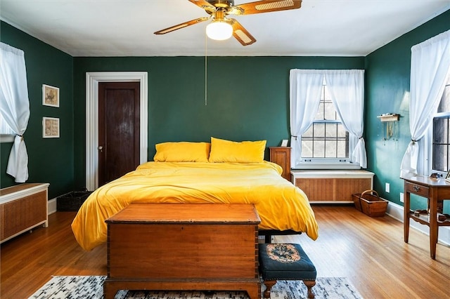 bedroom with ceiling fan, radiator, and hardwood / wood-style floors