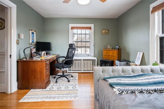 office space with radiator heating unit, ceiling fan, and light hardwood / wood-style flooring