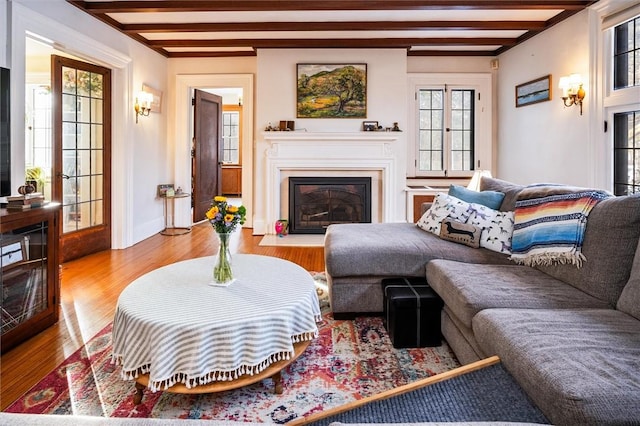 living room featuring beamed ceiling, plenty of natural light, french doors, and light wood-type flooring