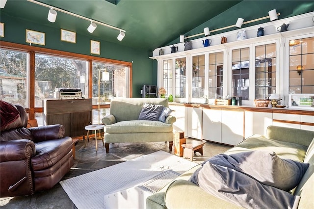 sunroom / solarium featuring rail lighting and vaulted ceiling