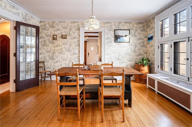 dining room featuring radiator heating unit, ornamental molding, and light wood-type flooring