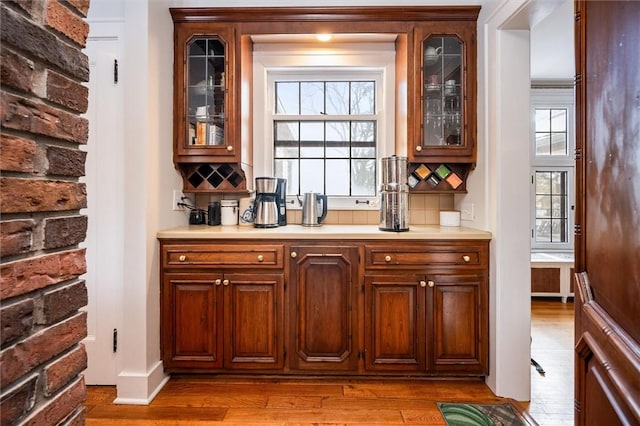 bar with decorative backsplash and light hardwood / wood-style floors