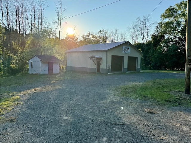 garage at dusk featuring a lawn