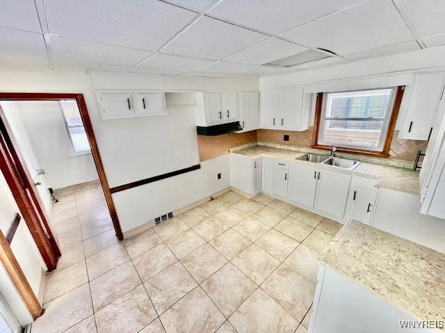 kitchen featuring sink, white cabinetry, extractor fan, a drop ceiling, and decorative backsplash