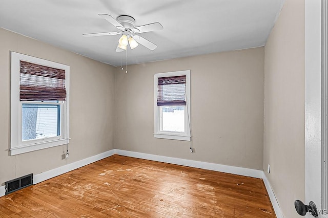 unfurnished room with ceiling fan, wood-type flooring, and a wealth of natural light