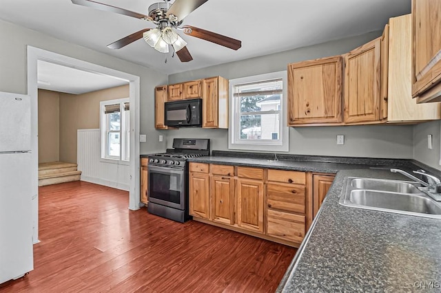 kitchen featuring sink, gas range, white refrigerator, dark hardwood / wood-style floors, and ceiling fan