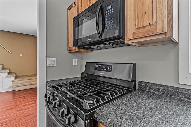 kitchen with dark hardwood / wood-style flooring and black appliances