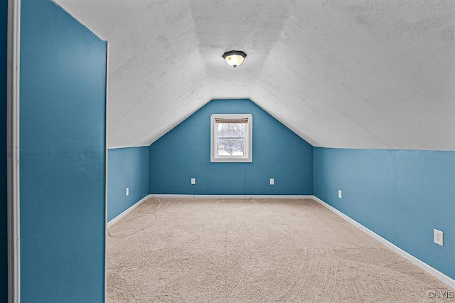 additional living space featuring lofted ceiling, carpet flooring, and a textured ceiling