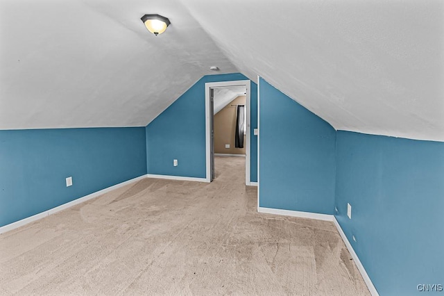 bonus room with light colored carpet and vaulted ceiling