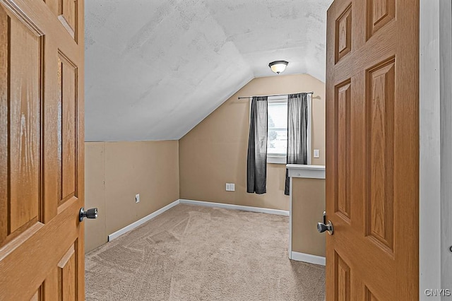 bonus room with vaulted ceiling, light colored carpet, and a textured ceiling