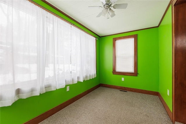 empty room with ornamental molding, plenty of natural light, light colored carpet, and ceiling fan