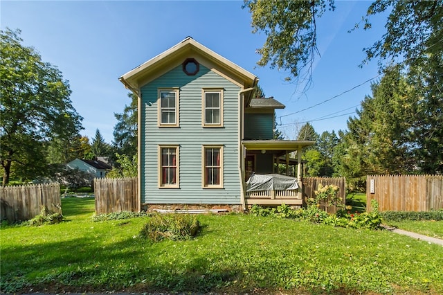 rear view of house with a wooden deck and a yard