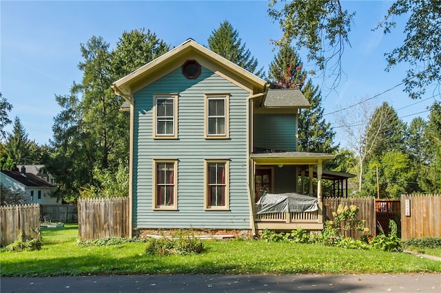 rear view of property featuring a porch and a yard