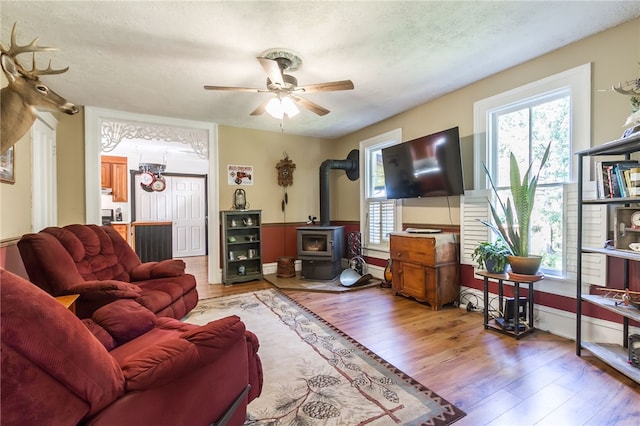 living room featuring plenty of natural light, a wood stove, hardwood / wood-style floors, and a textured ceiling