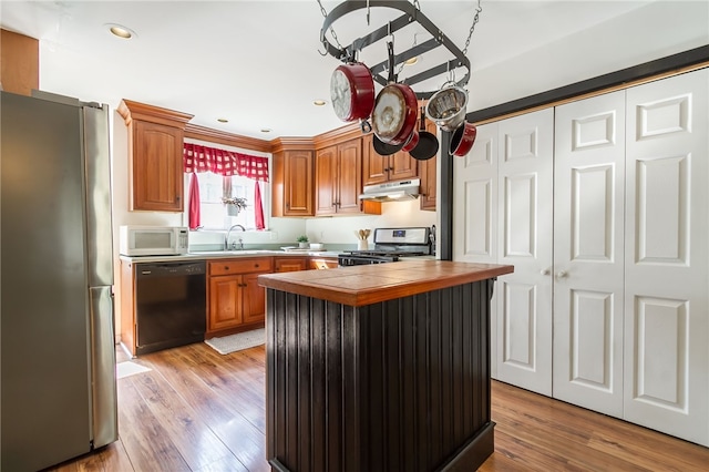 kitchen featuring stainless steel appliances, a center island, sink, and light hardwood / wood-style flooring