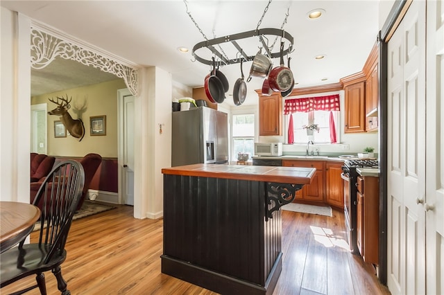 kitchen with a kitchen island, appliances with stainless steel finishes, sink, a breakfast bar area, and light hardwood / wood-style flooring