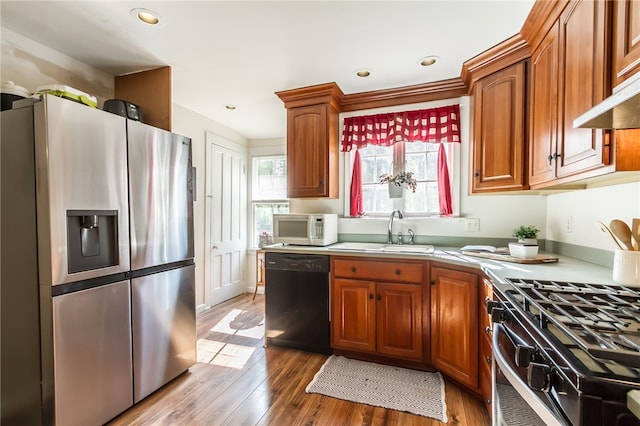 kitchen featuring sink, stainless steel fridge with ice dispenser, black dishwasher, range with gas stovetop, and light hardwood / wood-style floors