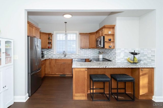 kitchen with a kitchen bar, light stone countertops, kitchen peninsula, and appliances with stainless steel finishes