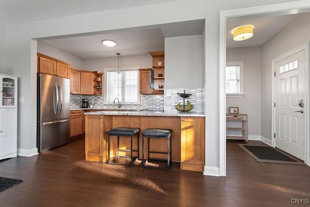 kitchen with backsplash, stainless steel fridge, kitchen peninsula, and a healthy amount of sunlight