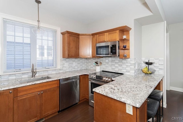 kitchen with sink, light stone countertops, hanging light fixtures, and appliances with stainless steel finishes