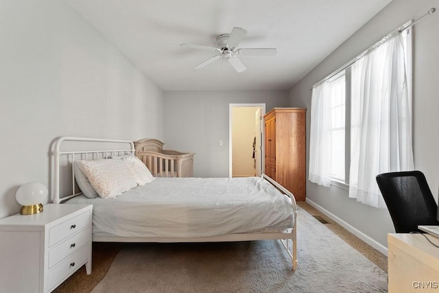 bedroom with multiple windows, ceiling fan, and light carpet