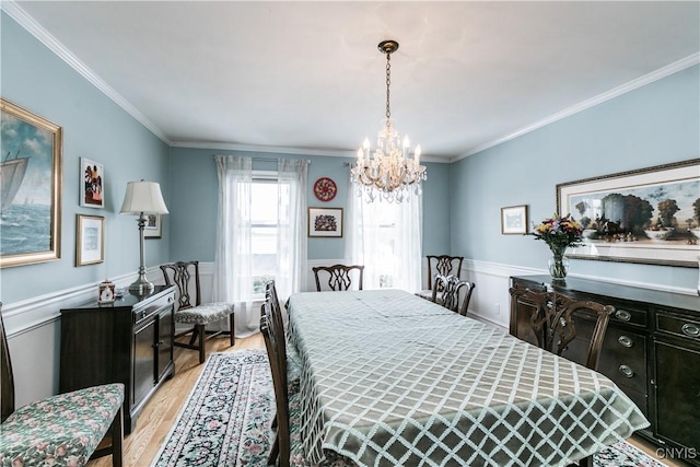 dining space with ornamental molding, a chandelier, and light hardwood / wood-style floors