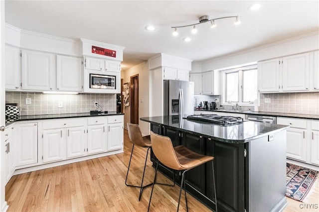 kitchen featuring stainless steel appliances, a center island, white cabinets, and light hardwood / wood-style flooring