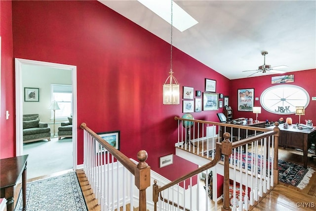 interior space with ceiling fan, high vaulted ceiling, a skylight, and hardwood / wood-style floors