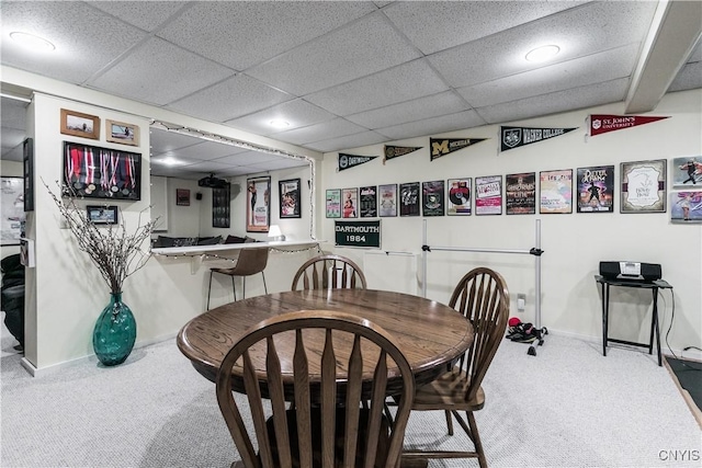 carpeted dining room with a drop ceiling