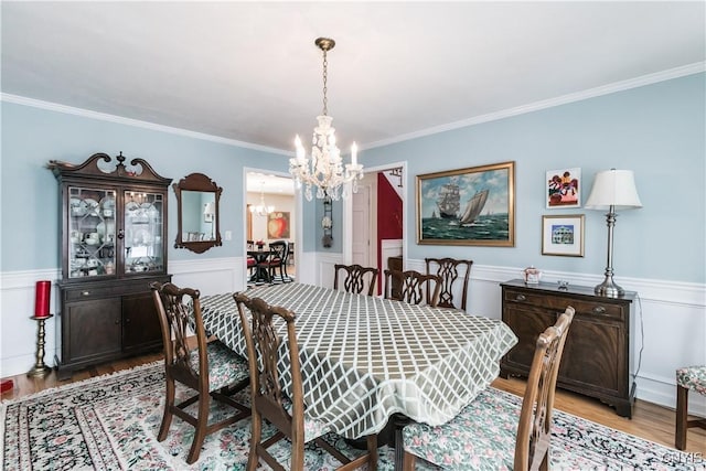 dining space featuring ornamental molding, a chandelier, and light hardwood / wood-style floors