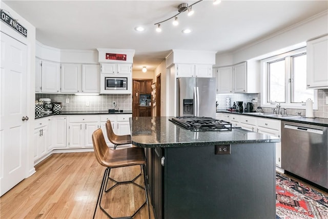 kitchen with stainless steel appliances, white cabinetry, a kitchen island, and sink