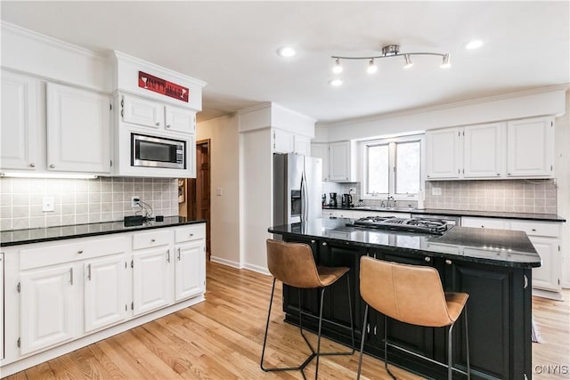 kitchen featuring white cabinetry, a kitchen breakfast bar, a center island, and appliances with stainless steel finishes