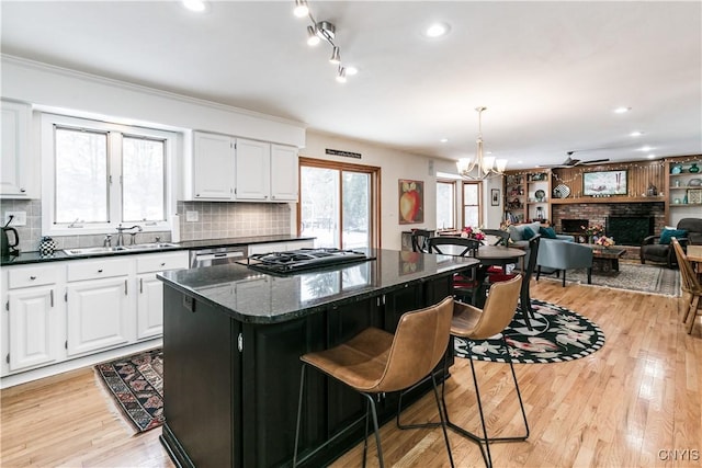 kitchen with white cabinetry, a center island, sink, and hanging light fixtures