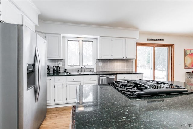 kitchen with sink, white cabinetry, crown molding, dark stone countertops, and stainless steel appliances