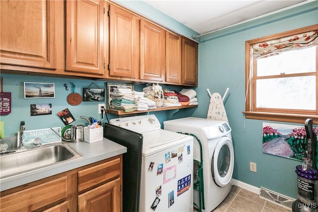 clothes washing area featuring washer and dryer, sink, light tile patterned floors, and cabinets