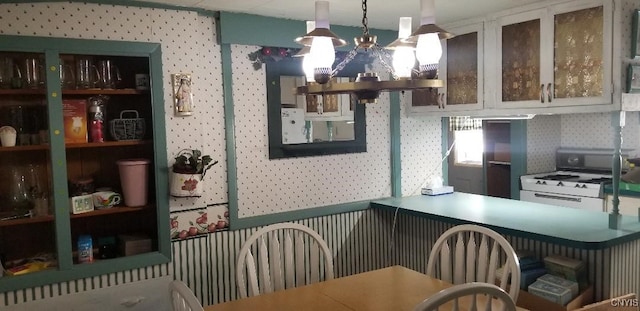 kitchen with white cabinetry, decorative light fixtures, and gas range gas stove