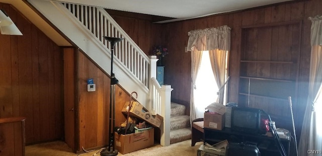 interior space featuring light colored carpet and wooden walls