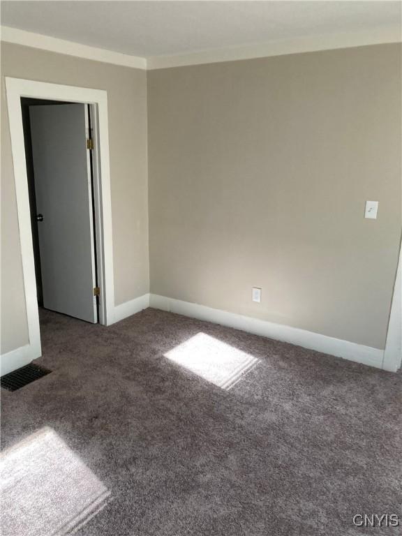 carpeted empty room featuring crown molding