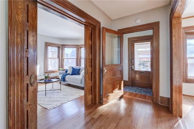 entryway with crown molding and light wood-type flooring