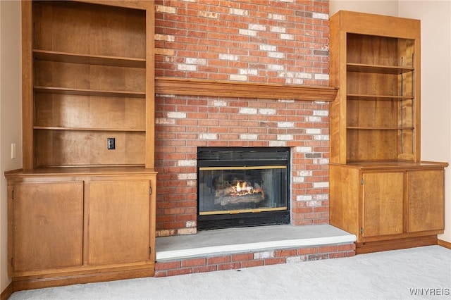 details with a brick fireplace, built in shelves, and carpet