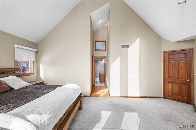 carpeted bedroom with ensuite bath and vaulted ceiling