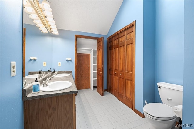 bathroom featuring vanity, tile patterned flooring, vaulted ceiling, and toilet