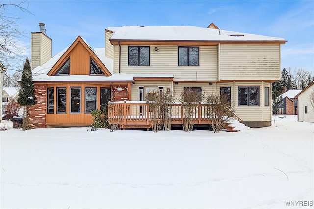 snow covered back of property featuring a wooden deck