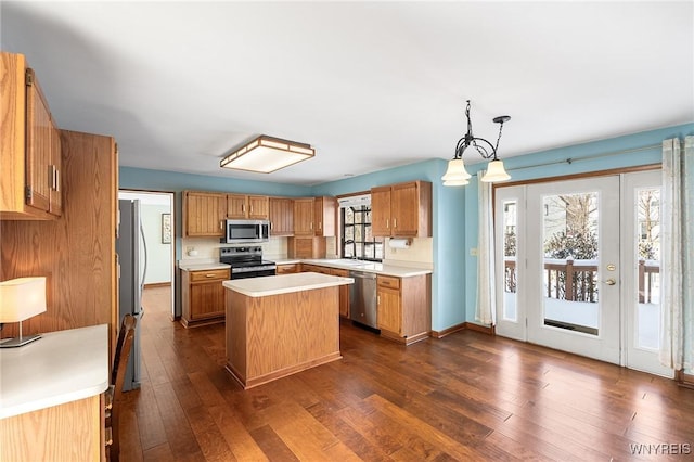 kitchen featuring dark wood-type flooring, tasteful backsplash, decorative light fixtures, a center island, and stainless steel appliances