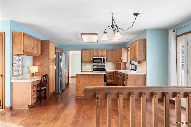 kitchen featuring pendant lighting, appliances with stainless steel finishes, tasteful backsplash, wood-type flooring, and a kitchen island