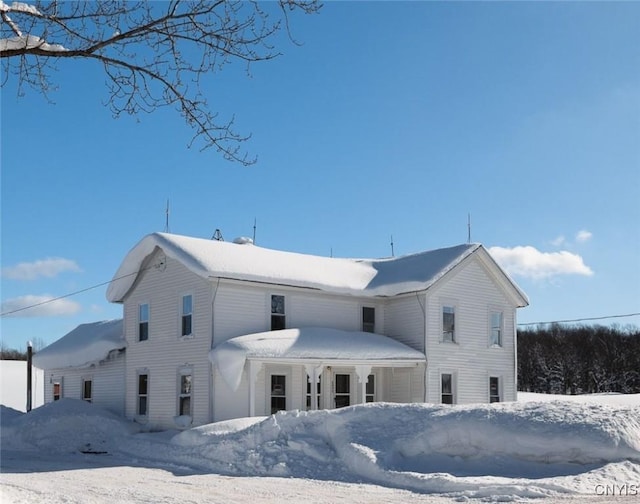 snow covered back of property featuring an attached garage
