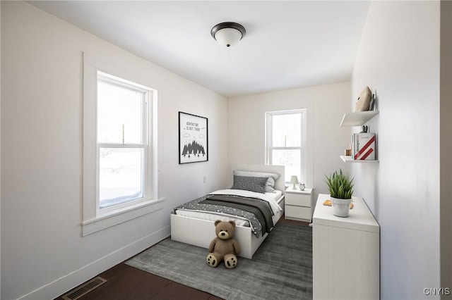 bedroom with baseboards, dark wood finished floors, and visible vents
