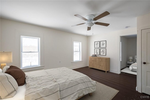 bedroom featuring multiple windows, dark wood-type flooring, and ceiling fan