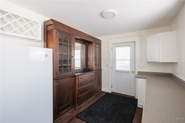 kitchen with white cabinetry, white refrigerator, and dark hardwood / wood-style flooring